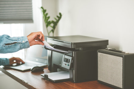 The man using multi-function laser printer in the home office.の写真素材