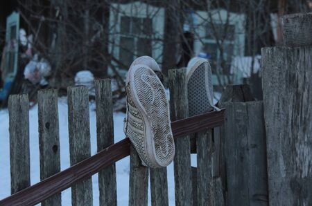 Old second-hand shoes on a fence in an abandoned villageのeditorial素材
