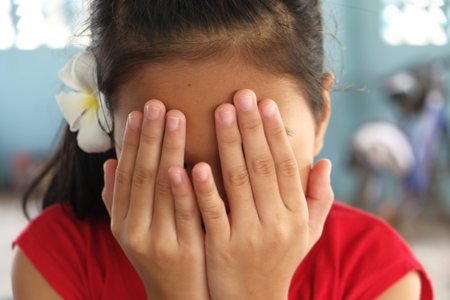 A young girl playing hide and seek covering his eyes with his handsの写真素材