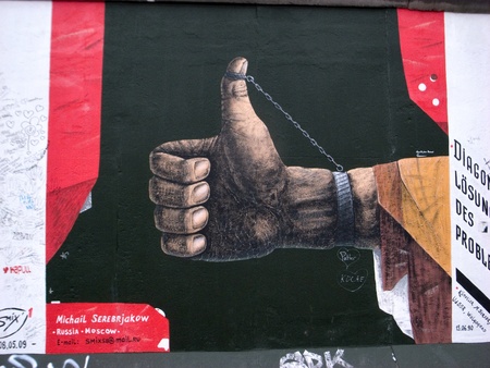 berlin germany, 20 february 2011:one of the many murals on the berlin wall; in this we can see the hand of a black person who raises his thumb to the sky, forced by a chainのeditorial素材
