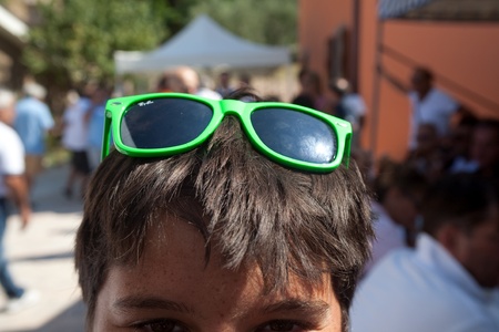 marche,italy- 28 august 2011:a boy wearing colored sunglasses, green, during a sunny dayのeditorial素材
