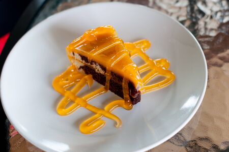 Chocolate layer cake with orange jam on a white plateの写真素材