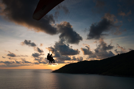 Paraglider flying at the sunset time at the shore of Phuket Thailandの写真素材