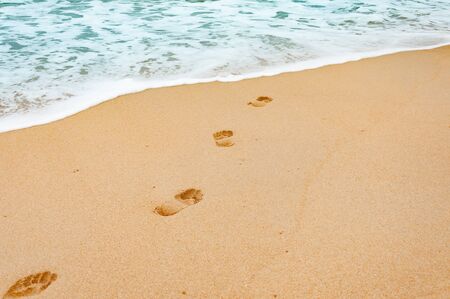 Footprints in the sea sandy beach on a relax vacation time in Phuket, Thailand