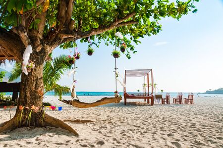 Swing hanging under a big tree for wedding ceremony decoration with pavilion and wedding arch on the beachの写真素材