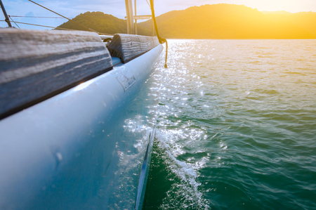 Selective focus of the luxury yacht's side cruising on the waves to the island in the evening. With...