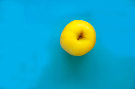 Close up yellow golden juicy apple isolated on a blue background. Top view pointの写真素材