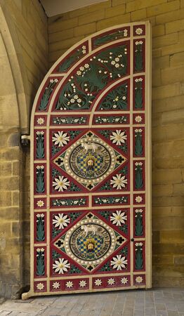 13 June 2018, Halifax, West Yorkshire, UK. Ornate, strong, wooden door at the entrance to the Piece Hall, Halifax. The door has a quadrant, displaying with red bordering and green floral motifsのeditorial素材