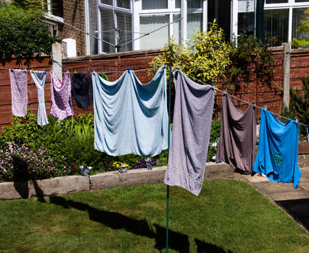 30 May 2020, Leeds, UK. Clothes drying on a domestic line in a back garden. A bright sunny, breezy day ensures quick drying and benefits the surrounding flowers, plants and green lawn.のeditorial素材