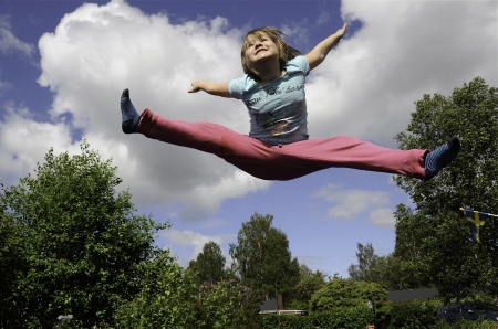 Happy jumping girl on a blue sky backgroundの写真素材