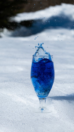 Blue water splash out of a glass on a snowdrift.の写真素材