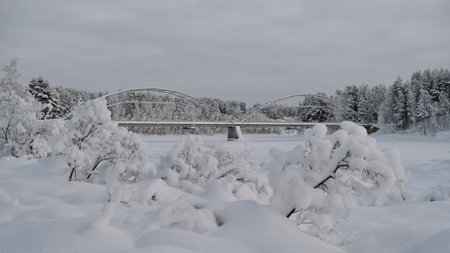Bridge over the river in the winter forest. Beautiful winter landscape.の写真素材