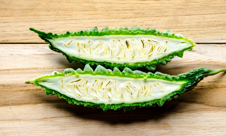 Close up of fresh bitter gourd fruit with half isolated on wooden backgroundの写真素材