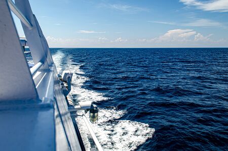 Close up white railing ferry boat against blue seaの写真素材