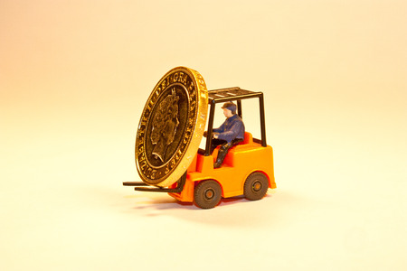 A toy forklift truck lifting up a British two pound coinの写真素材