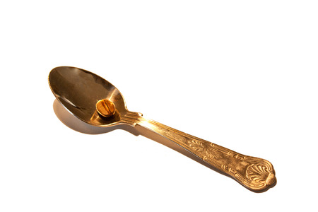 Spoon with single coffee bean on white backgroundの写真素材