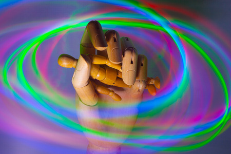 A wooden hand holding a mannequin person within swirling lightsの写真素材