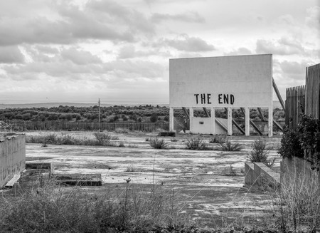 An old cinema billboard has the deep words of 'The End' painted onto a blank board, in a degraded parking lot.の写真素材