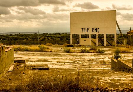 An old cinema billboard has the deep words of 'The End' painted onto a blank board, in a degraded parking lot.の写真素材