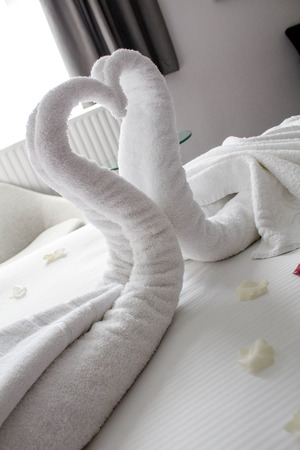 A pair of beautifully designed swans sitting on a bed in a hotel room ready to welcome a couple.の写真素材