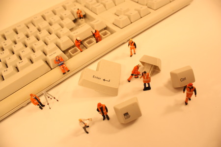 A close up view of miniature plastic figures working on a computer keyboard.の写真素材