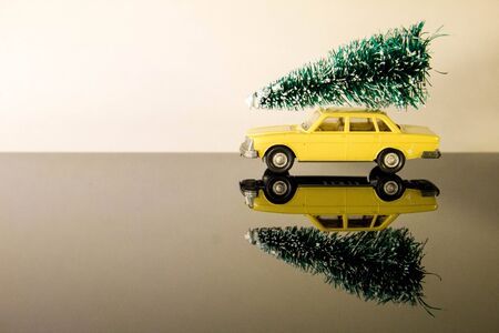 A car against a blank background sits with a lovely green Christmas tree on the roof.