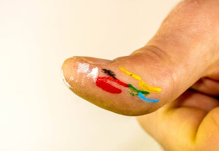 A thumb of an artist with various colours of paint on it.の写真素材