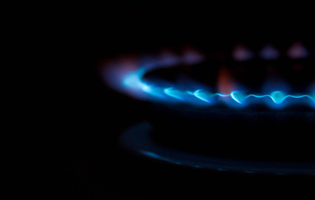 A bright neon blue flame emitting from a cooker hob.