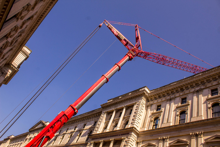 A huge red crane operates in the middle of an area of London city.の写真素材