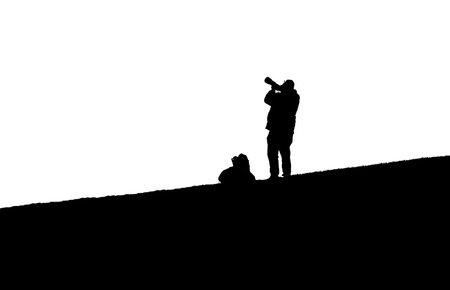 A black and white image of a silhouetted photographer on a hill.の写真素材