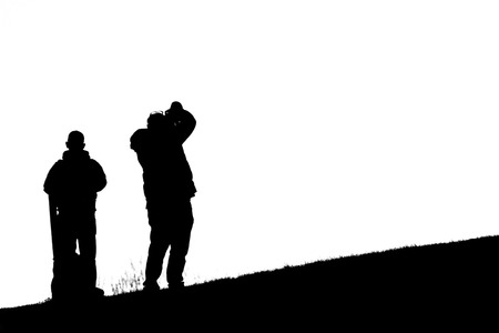 A black and white image of a silhouetted photographer on a hill.の写真素材