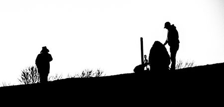 A black and white image of a silhouetted photographer on a hill.の写真素材
