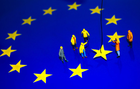 A team of construction workers work to remove a yellow star from the EU flag, representing Brexit.