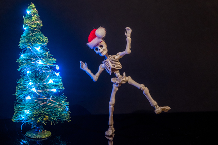 A skeleton dancing around a Christmas Tree with lights.の写真素材