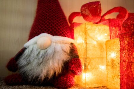 A Christmas Gonk sits alongside lighted presents.の写真素材
