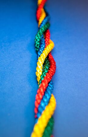 Colourful primary coloured string twisted on a bright blue background.