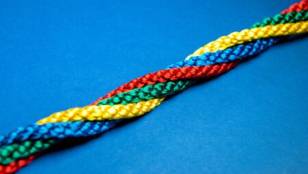 Colourful primary coloured string twisted on a bright blue background.