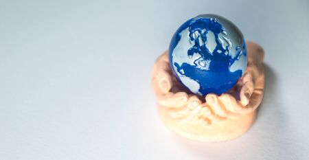 A cupped set of hands holds a miniature version of planet Earth.の写真素材