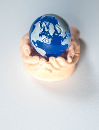 A cupped set of hands holds a miniature version of planet Earth.の写真素材