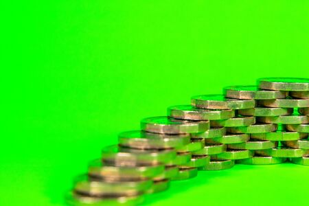 A pile of Pound Coins stacked against a green background.の写真素材