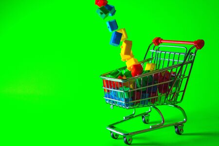A supermarket trolley full of plastic houses. Taken against a solid green screen color.の写真素材