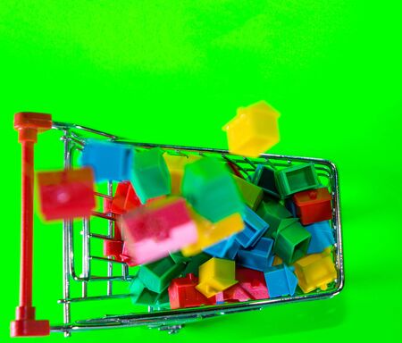 A supermarket trolley full of plastic houses. Taken against a solid green screen color.の写真素材
