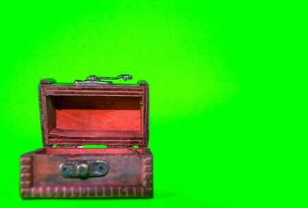 A small toy wooden chest, taken against a bright green screen background.