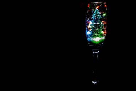 A champagne glass with a Christmas tree, lights and snow bringing that festive celebration.の写真素材