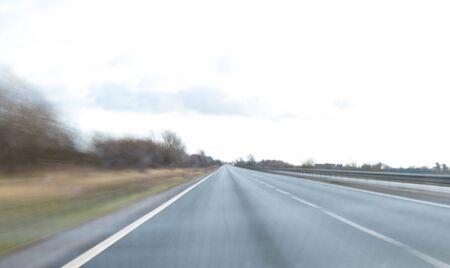 A view along a main road with motion blur showing the movement of traffic and the vehicle being...