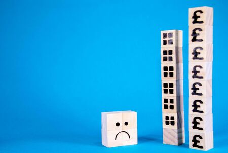 The cost of housing is a huge issue nationally and internationally. Here wooden blocks with symbols...