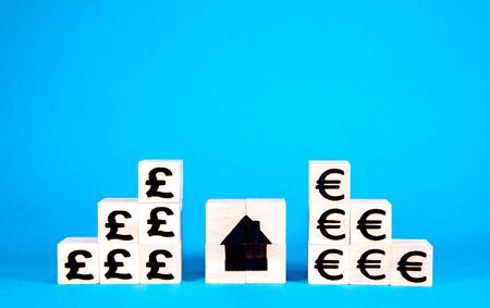 The cost of housing is a huge issue nationally and internationally. Here wooden blocks with symbols...