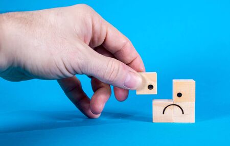 A very sad looking face on wooden blocks, the face showing sadness and depression emotions.