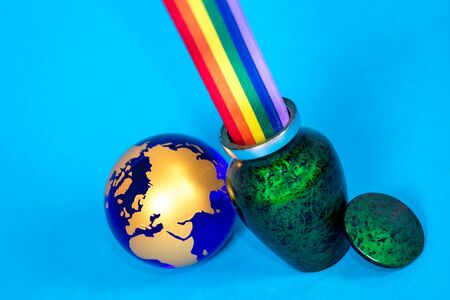 A small green ceramic ashes urn with a colorful rainbow coming out the top.の写真素材