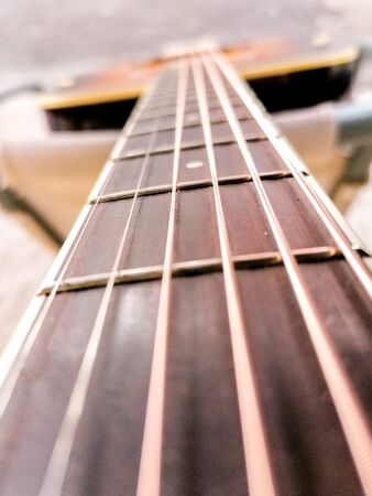 An acoustic guitar view from the top alone the strings.